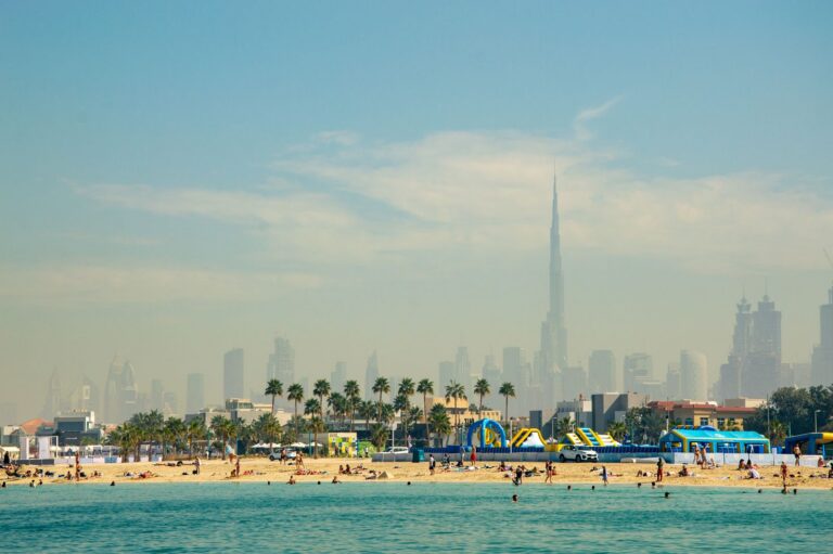 Tourists enjoying a sunny day at a Dubai beach with the Burj Khalifa and skyline in the background